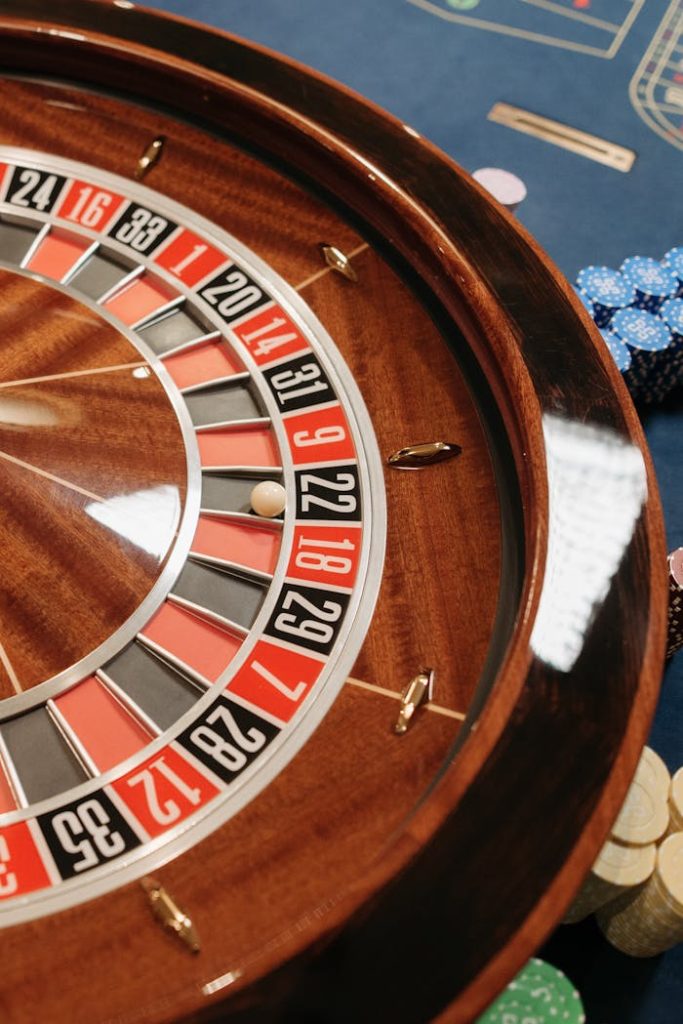 Close-up of a roulette wheel with poker chips in a casino setting, highlighting chance and gambling.
